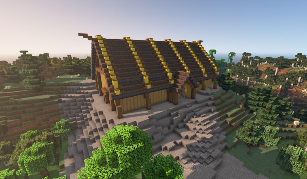 A minecraft rendition of a viking mead hall. The long side has a jutting out door and there is a small door on the far left side. The walls and supports are made from wooden beams, and the roof is dark stone with stripes of gold running perpendicular to the length of the hall.